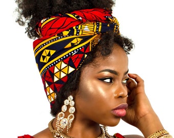 Puede incluir: Una mujer con cabello oscuro y rizado lleva una envoltura para la cabeza con estampado rojo, amarillo y azul. También lleva un collar y pendientes de oro, y pulseras de oro en la muñeca.