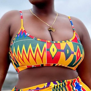 Op de afbeelding: Een tweedelig badpak met een kleurrijk Afrikaans printpatroon. De top is halter-stijl met een dunne band en de onderkant is een hoge taille bikini broek. Het badpak is gemaakt van een zachte, rekbare stof en is perfect voor een dag op het strand of bij het zwembad.