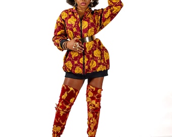 May include: A woman wearing a red and gold patterned jacket with a black zipper and a gold belt. She is also wearing red and gold patterned thigh-high boots.