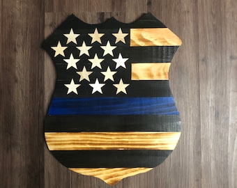 May include: Wooden American flag shield with a blue line, representing law enforcement.