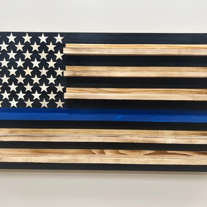 May include: Wooden wall shelf in the shape of an American flag with a blue stripe. The shelf has five shelves for displaying items.