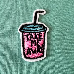 May include: Pink and white embroidered patch of a cup with a straw and the text "Take Me Away".