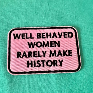 Può includere: Toppa in tessuto rosa con testo ricamato in nero che recita "Well Behaved Women Rarely Make History".