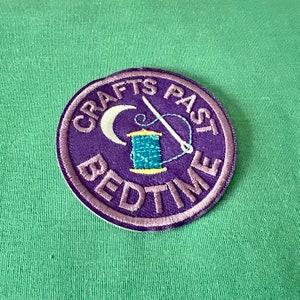 May include: Purple embroidered patch with the text "Crafts Past Bedtime" and a crescent moon, needle, and spool of thread.