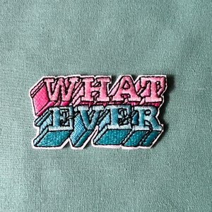 May include: A pink and blue embroidered patch with the text "WHAT EVER" in a retro font style.