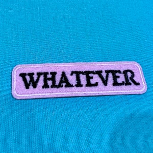 May include: A purple fabric patch with white stitching around the edges. The patch has the word "WHATEVER" embroidered in black thread.