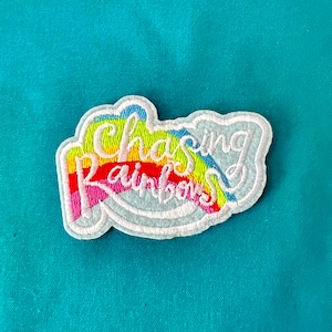May include: A white embroidered patch with a rainbow and the text "Chasing Rainbows".