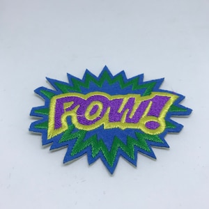 Può includere: Una toppa ricamata blu, verde e gialla con la parola "POW!" in stile fumetto.