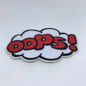 Pode incluir: Etiqueta bordada vermelha com a palavra "oops!" em forma de nuvem branca.