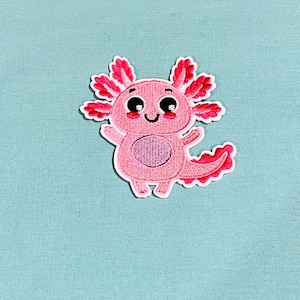 May include: Pink embroidered axolotl patch with big eyes and a smile. The axolotl is a type of salamander.