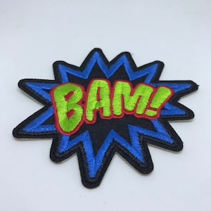 Könnte beinhalten: Ein gestickter Aufnäher in Blau und Schwarz mit dem Wort "BAM!" in grünen und roten Buchstaben.