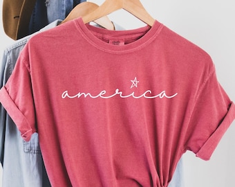 May include: A red t-shirt with the word "america" written in white cursive with a small star above the "a".