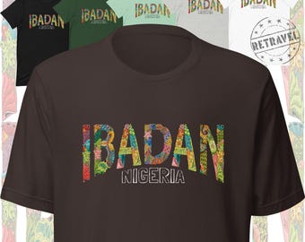Puede incluir: Varias camisetas de manga corta en varios colores, como negro, verde y blanco. Cada camiseta muestra la palabra "IBADAN" en un diseño floral colorido, con "NIGERIA" debajo. También es visible un sello "RETRAVEL".