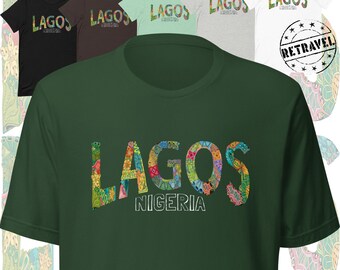 Puede incluir: Una colección de camisetas de manga corta en varios colores, incluyendo negro, marrón, verde y blanco. Cada camiseta presenta la palabra "LAGOS" en un diseño colorido y estampado, con "NIGERIA" impreso debajo. Un sello "RETRAVEL" es visible.