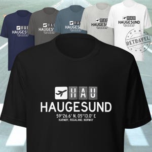 May include: Several short-sleeved t-shirts in shades of black, navy, grey, and white. Each shirt displays the word "HAUGESUND" in white, accompanied by the coordinates 59°26.6' N, 05°13.0' E, and the text "KARMØY, ROGALAND, NORWAY".