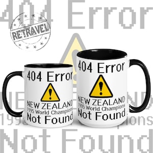 May include: Two white coffee mugs with black rims. The mugs have a black and yellow warning sign with an exclamation point and the text "404 Error" and "New Zealand 1995 World Champions Not Found".