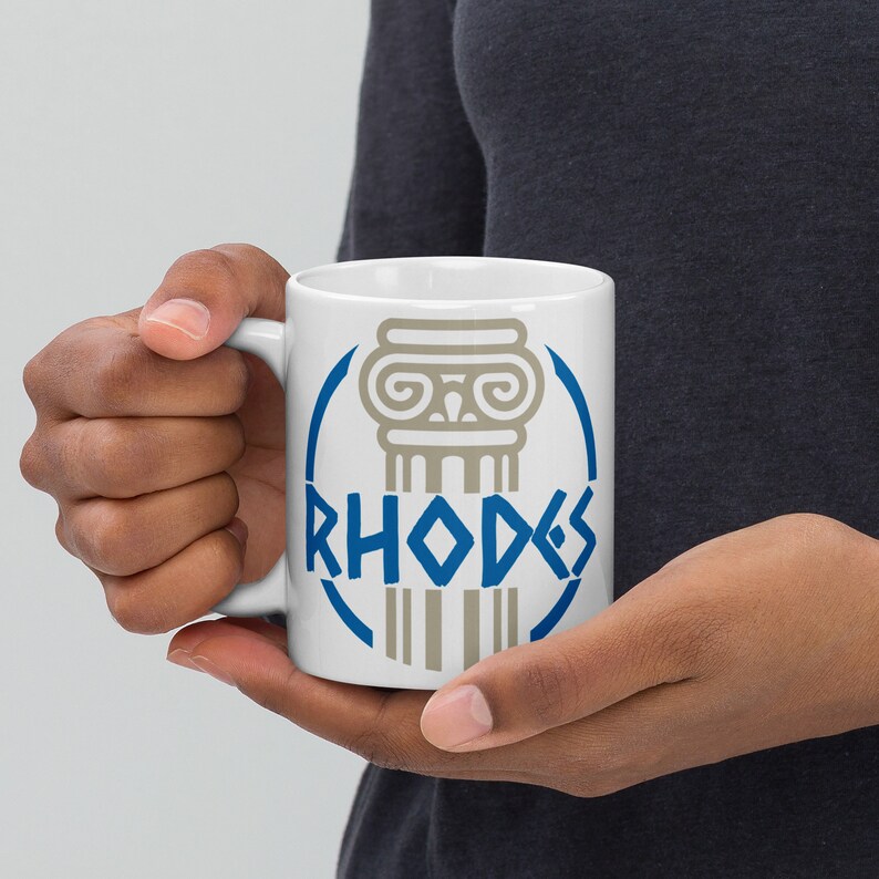 May include: White ceramic mug with a blue circle design featuring a gray column and the word "RHODES" in blue lettering.