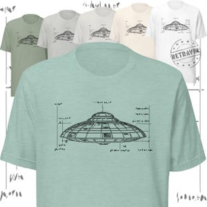 Op de afbeelding: Een collectie t-shirts met korte mouwen in verschillende kleuren, elk met een gedetailleerde illustratie in blauwdrukstijl van een UFO. Het ontwerp bevat technische annotaties en afmetingen. De shirts zijn in tinten groen, grijs, wit en crème.