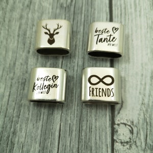 May include: Four silver charm bracelets with different engraved designs. The charms feature a deer, the words "Beste Tante der Welt", "Beste Kollegin der Welt", and "Friends" with an infinity symbol.