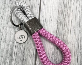 May include: A pink and white rope keychain with a silver metal tag that says "Jan" with a star.