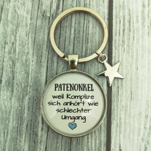 Può includere: Un portachiavi d'argento con un ciondolo rotondo di vetro che dice "Patenonkel weil Komplize sich anhört wie schlechter Umgang" con un cuore blu.
