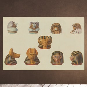 May include: A collection of nine Egyptian-style decorative heads with various animal and human features. The heads are painted in gold, black, and white with intricate details. The heads are arranged in a grid pattern on a cream-colored background.