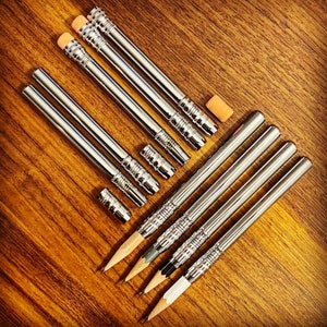 May include: A set of ten silver mechanical pencils with erasers. The pencils are arranged in two rows, with the erasers facing up. The pencils are all the same size and have a sleek, modern design.