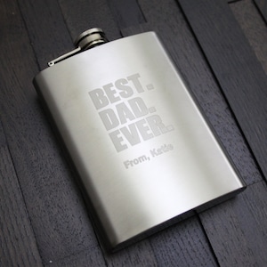 May include: A silver stainless steel flask with the text "BEST. DAD. EVER." and "From, Katie" engraved on it.