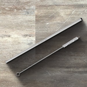 May include: A silver metal drinking straw with the text "SAMUEL LEE" printed on it and a silver metal cleaning brush with white bristles.