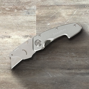 May include: A silver utility knife with a retractable blade and a personalized inscription that reads "Jonathan".
