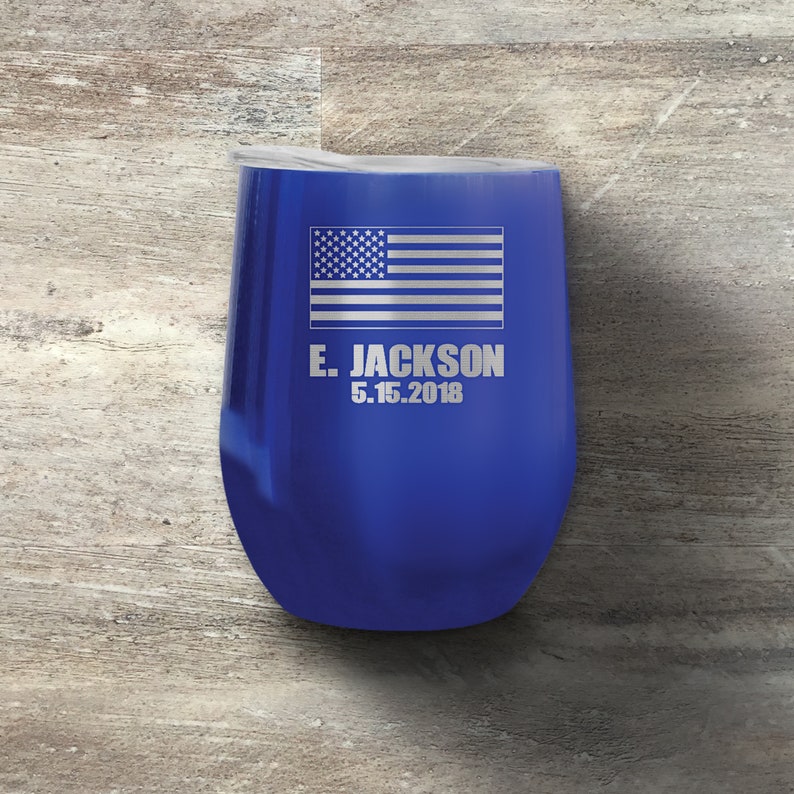 以下が含まれることがあります： 銀色のアメリカ国旗と「E. JACKSON 5.15.2018」という文字が刻まれた、青いステンレス製のワインタンブラーです。