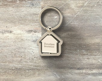 May include: Silver house-shaped keychain with a silver ring. The keychain has the name "Jonathan Sturdevant" engraved on it.
