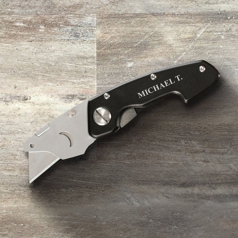May include: A black utility knife with a silver blade and a personalized inscription that reads "MICHAEL T."