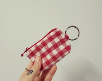 Puede incluir: Un monedero de llavero de gingham rojo y blanco con un llavero plateado.