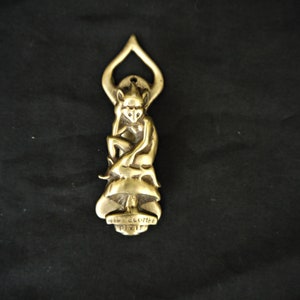 May include: A brass door knocker shaped like a pixie sitting on a mushroom. The knocker has a detailed design and says "Welcome Pixie" on the bottom.