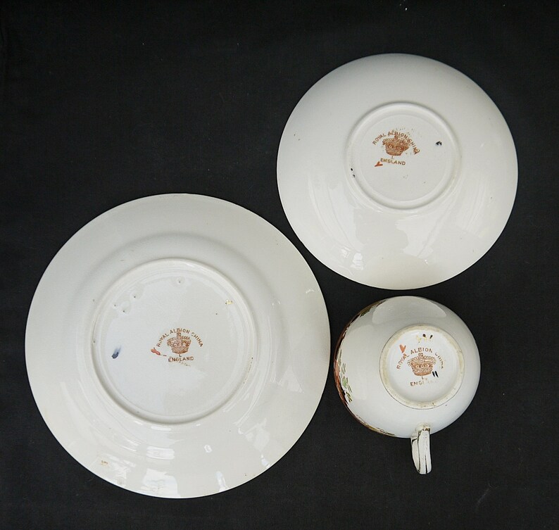 May include: Three white porcelain teacups and saucers with a floral design. The bottom of each piece has a brown stamp that reads "Royal Albert China England".