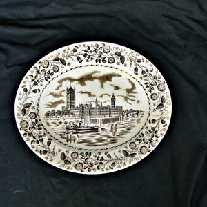 May include: A white oval ceramic serving platter with a brown floral border and a brown image of the Houses of Parliament in London, England.