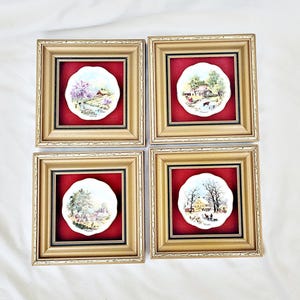 May include: Set of four framed decorative plates with a red mount and gold frame. Each plate features a different countryside scene with a white background.