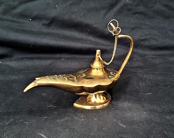Könnte beinhalten: Eine goldene Dschinnenlampe mit filigranen Details und einer Kette, die an dem Griff befestigt ist.