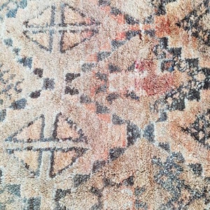 May include: A close-up of a beige and brown rug with a geometric pattern. The rug has a soft, fuzzy texture.