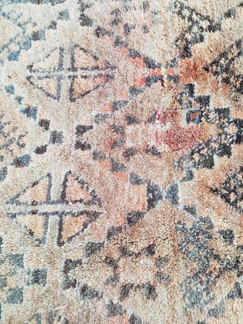 May include: A close-up of a beige and brown rug with a geometric pattern. The rug has a soft, fuzzy texture.