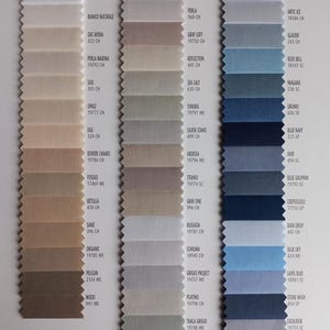 May include: A fabric sample swatch card featuring three vertical columns of rectangular textile strips with pinked edges. The swatches display a gradient of neutral, gray, and blue color tones, each labeled with specific color names and codes.