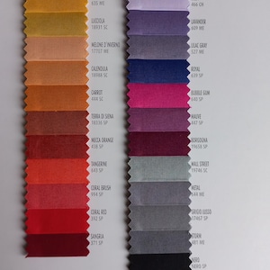 May include: Two vertical columns of fabric swatches with pinked edges. The left column displays warm tones from yellow to deep red, labeled with names like Pine Apple, Lucciola, and Sangria. The right column shows cool tones from lavender to black, labeled with names like Lilla, Royal, and Nero.