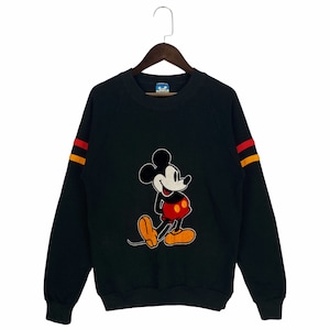 Puede incluir: Sudadera negra con un gráfico vintage de Mickey Mouse en la parte delantera. La sudadera tiene rayas amarillas y rojas en las mangas.