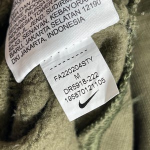 Op de afbeelding: Een witte keramische mok met een zwarte handgreep en de tekst "But First, Coffee" in een vetgedrukte, zwarte letter. De mok staat tegen een vage achtergrond, wat een gezellige setting suggereert.