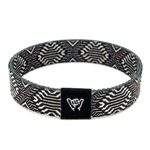 May include: Black and white patterned woven bracelet with a black adjustable buckle featuring a white "shaka" hand gesture symbol.