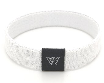 May include: White woven wristband with a black label featuring a hand gesture symbol.