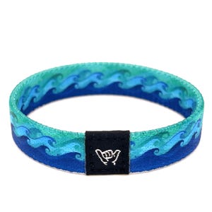 Könnte beinhalten: Ein blaues und grünes gewebtes Armband mit Wellenmuster und einer schwarzen verstellbaren Schnalle mit einer weißen "Shaka"-Handgeste.
