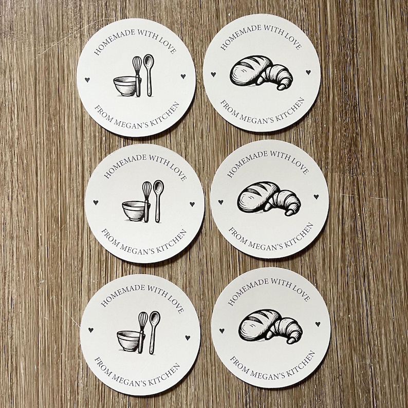 Puede incluir: Seis pegatinas redondas blancas con ilustraciones y texto en negro. Las pegatinas presentan dibujos de utensilios de cocina y productos horneados. El texto dice "Homemade with Love" y "From Megan's Kitchen."