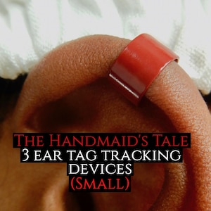 May include: Three small, red, ear tag tracking devices. The text "THE HANDMAID'S TALE 3 EAR TAG TRACKING DEVICES (SMALL)" is printed below the devices.